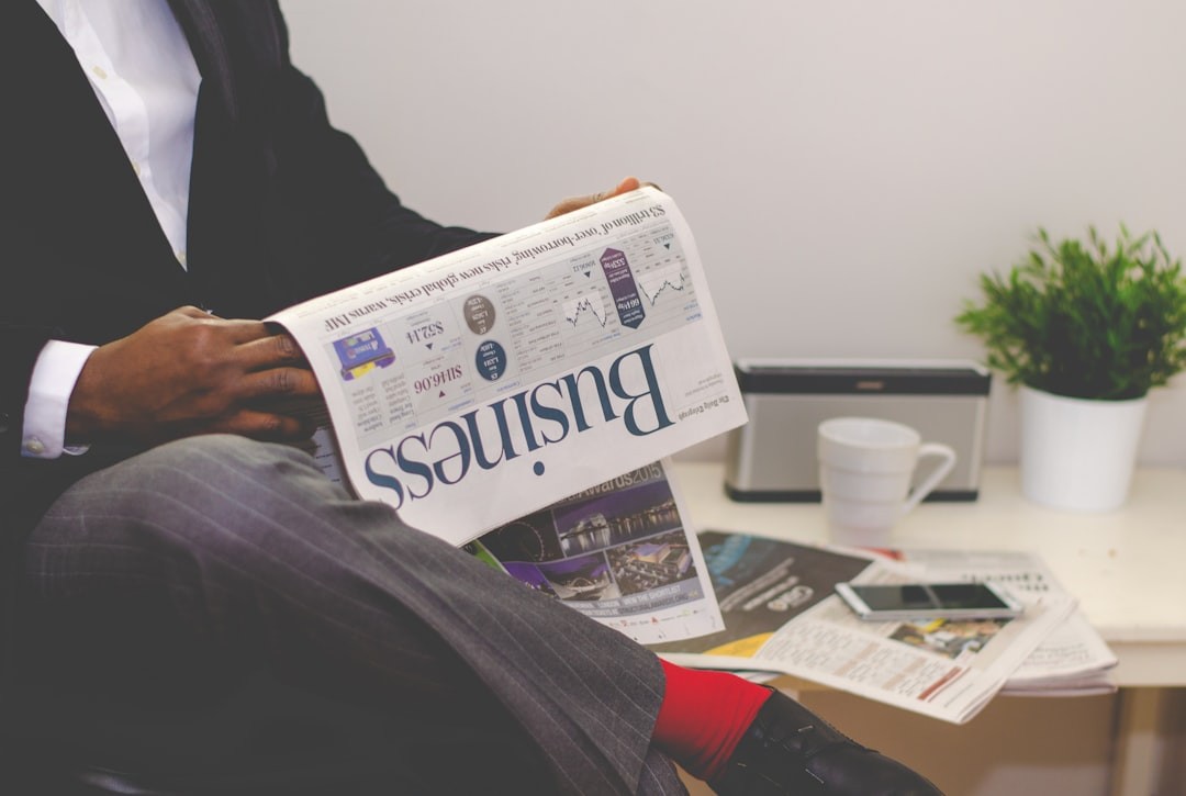 person sitting near table holding newspaper person sitting near table holding newspaper